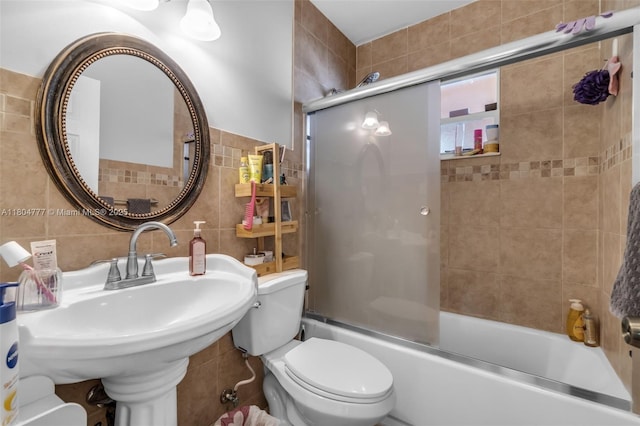 bathroom with tile walls, toilet, enclosed tub / shower combo, tasteful backsplash, and a sink