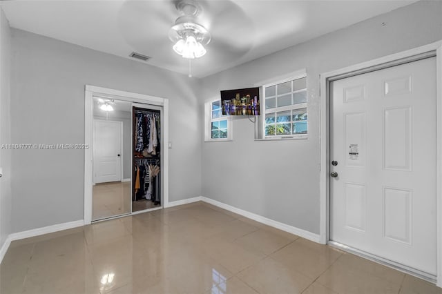 foyer with a ceiling fan, baseboards, and tile patterned floors