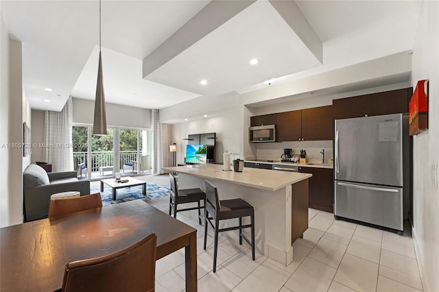 kitchen with stainless steel appliances, open floor plan, light countertops, a breakfast bar, and recessed lighting