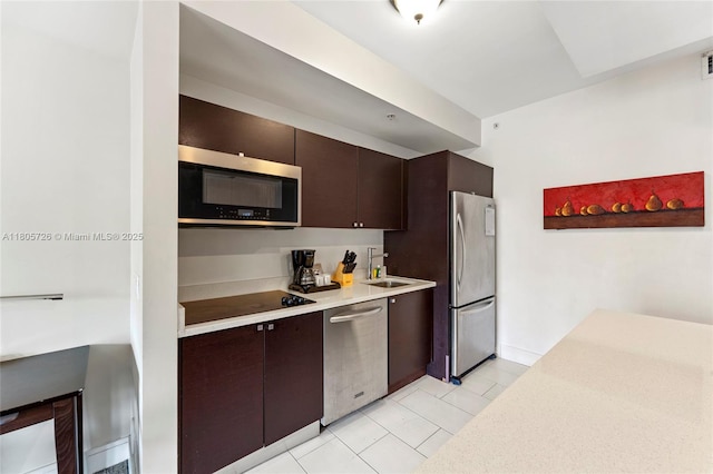 kitchen with stainless steel appliances, a sink, dark brown cabinets, and light countertops