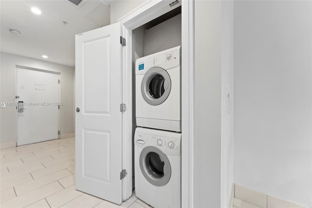laundry area featuring stacked washer / drying machine, recessed lighting, light tile patterned flooring, and baseboards