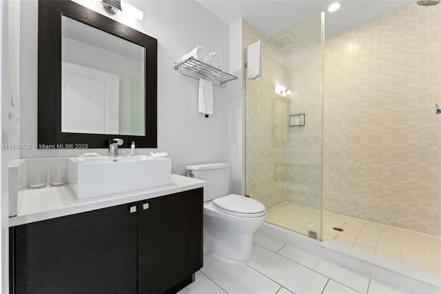 bathroom with a tile shower, tile patterned flooring, toilet, and vanity
