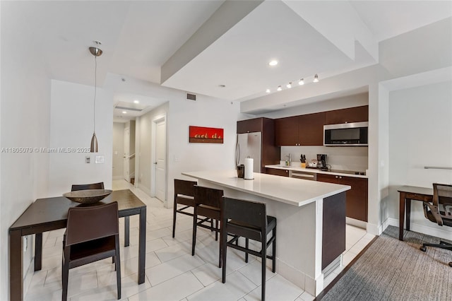 kitchen with stainless steel appliances, a breakfast bar area, light countertops, modern cabinets, and dark brown cabinetry
