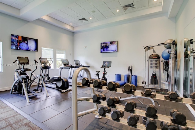workout area featuring a tray ceiling and a high ceiling