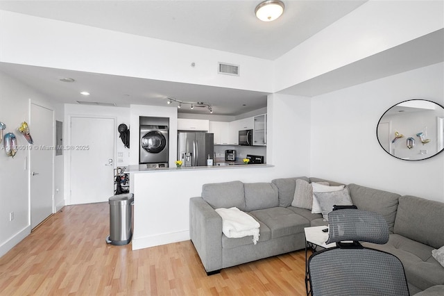 350 NE 24th St Unit 714, Miami, FL 33137 - living room featuring estacked washer and dryer, light wood-style floors, and baseboards