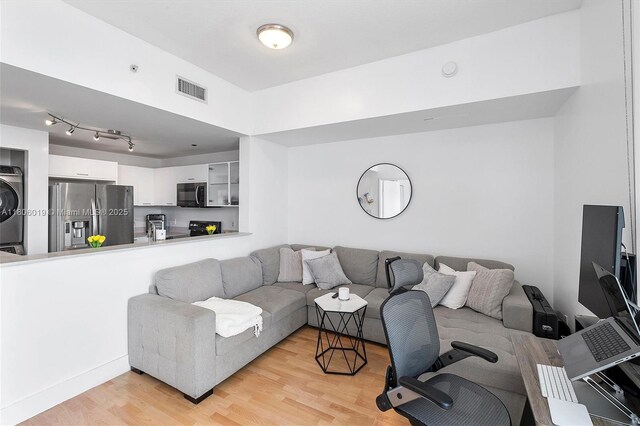 350 NE 24th St Unit 714, Miami, FL 33137 - living area with stacked washer / dryer and light wood-style flooring