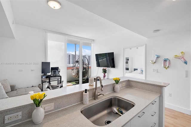 350 NE 24th St Unit 714, Miami, FL 33137 - kitchen with a sink, open floor plan, light stone counters, and white cabinets