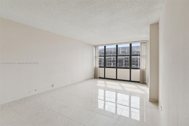 1901 Brickell Ave Unit B1408, Miami, FL 33129 - empty room featuring a textured ceiling, light tile patterned flooring, baseboards, and floor to ceiling windows