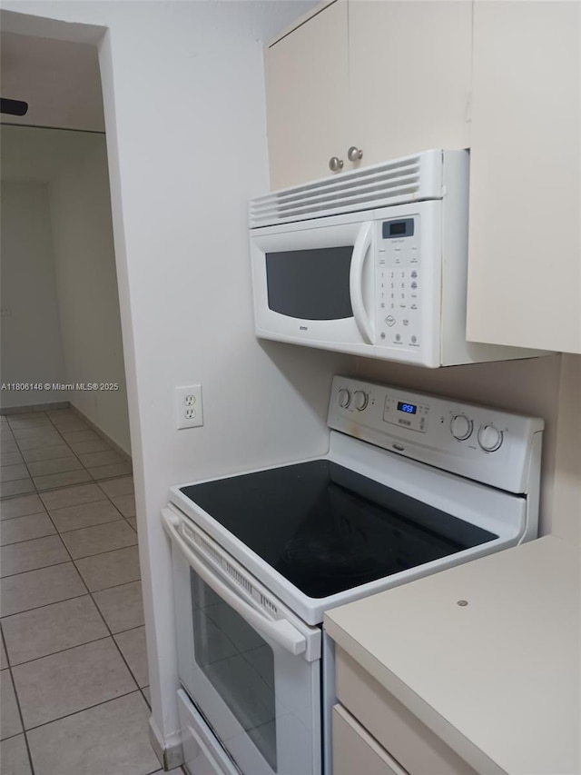 2700 NE 135th St Unit 30, North Miami, FL 33181 - kitchen featuring white appliances, light tile patterned floors, light countertops, and white cabinets