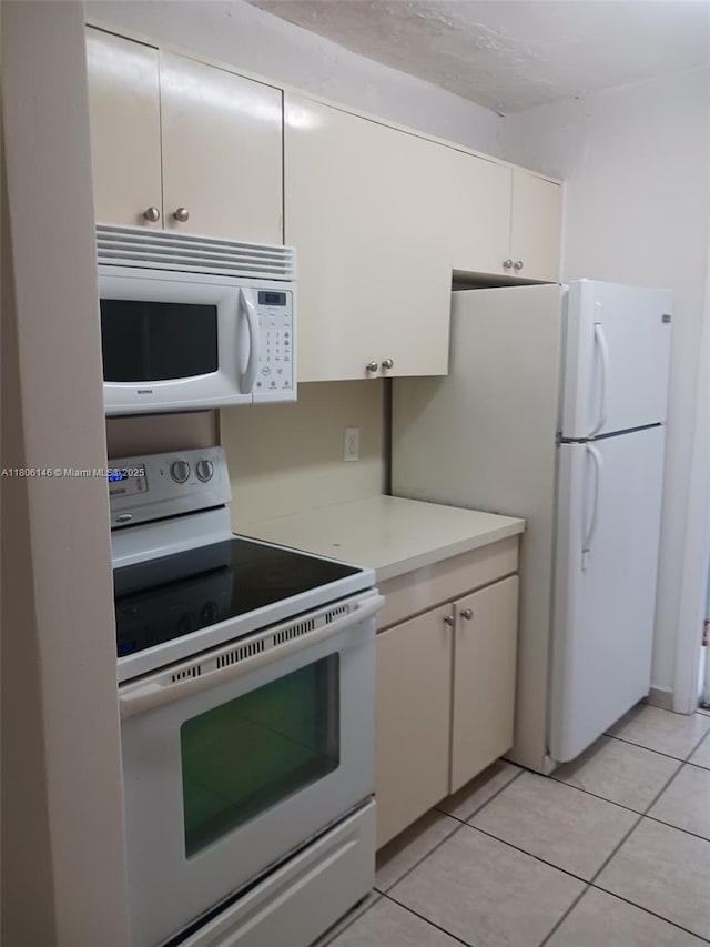 2700 NE 135th St Unit 30, North Miami, FL 33181 - kitchen featuring white appliances, light countertops, light tile patterned floors, and white cabinetry