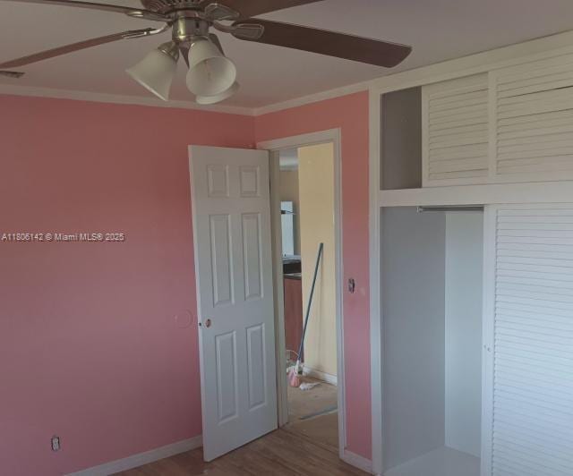 884 Montego Dr, West Palm Beach, FL 33415 - unfurnished bedroom featuring a closet, wood finished floors, ornamental molding, ceiling fan, and baseboards
