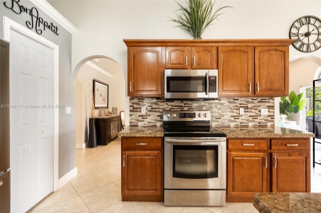 921 SW 176th Ave, Pembroke Pines, FL 33029 - kitchen with stainless steel appliances, decorative backsplash, dark stone counters, arched walkways, and ornamental molding