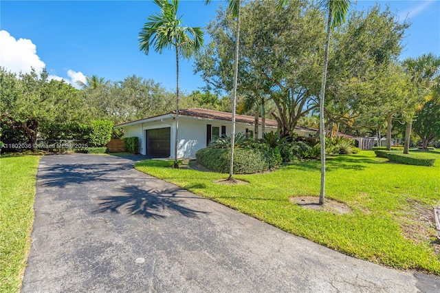 view of front of house with asphalt driveway, a front lawn, a garage, and stucco siding