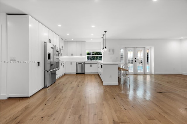 kitchen featuring appliances with stainless steel finishes, a breakfast bar area, light countertops, a peninsula, and french doors