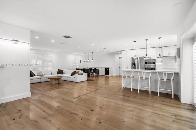 living room featuring recessed lighting, light wood-style flooring, and baseboards