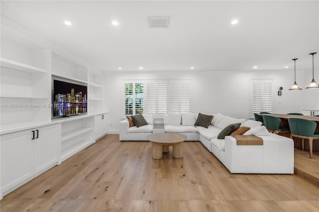 living area featuring recessed lighting, light wood finished floors, and built in shelves