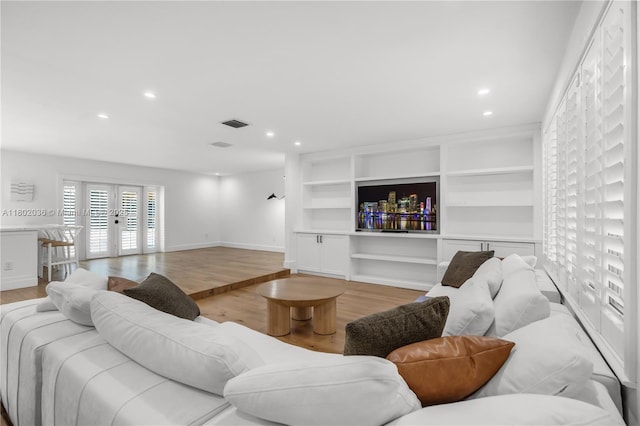 living room featuring light wood-style floors, baseboards, french doors, built in shelves, and recessed lighting