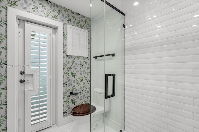 bathroom with wallpapered walls, a shower stall, toilet, and baseboards