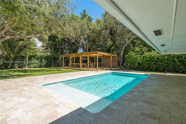 view of swimming pool featuring a patio area, view of scattered trees, and a yard