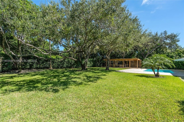 view of grassy yard featuring an outdoor pool and a patio area