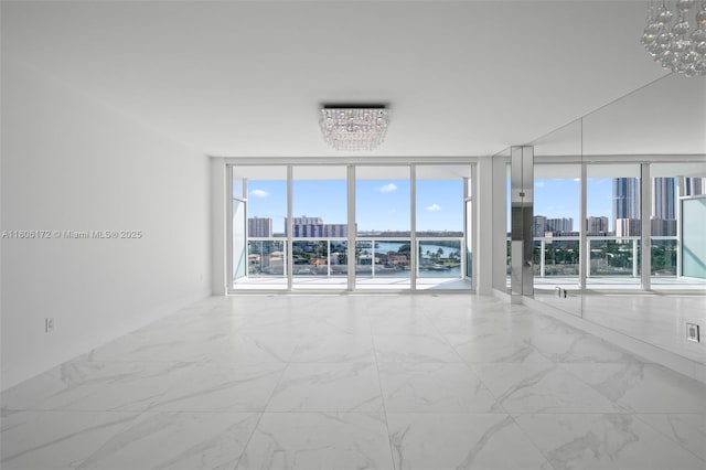400 Sunny Isles Blvd Unit 1005, Sunny Isles Beach, FL 33160 - empty room featuring a chandelier, a skyline view, expansive windows, and marble finish floors