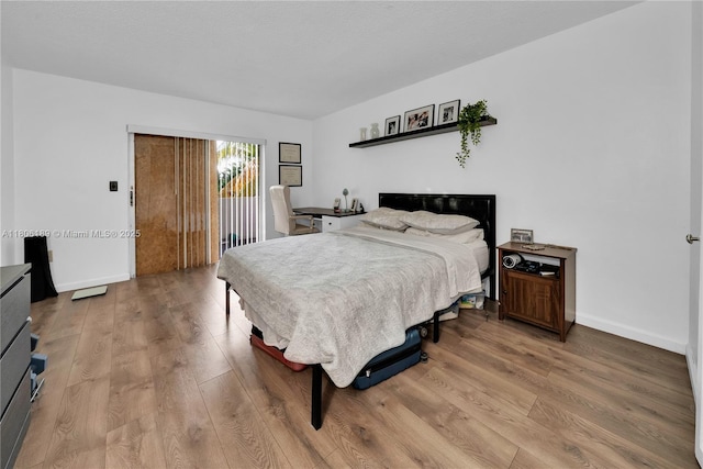 bedroom with access to outside, light wood finished floors, and baseboards