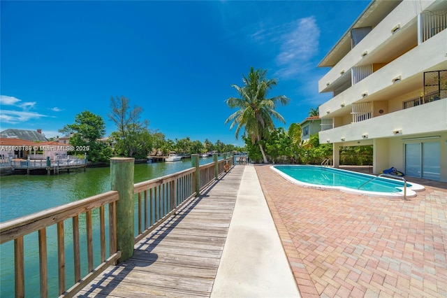 view of swimming pool featuring a water view and a patio area