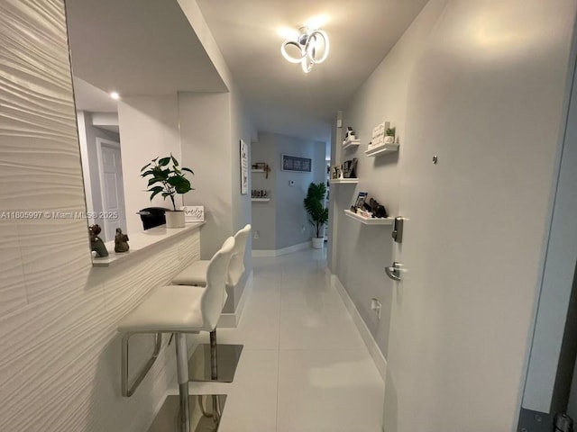 corridor featuring light tile patterned floors and baseboards