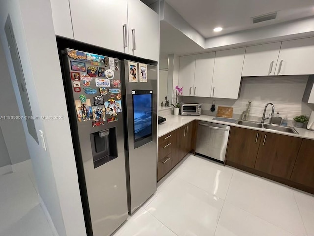 kitchen with stainless steel appliances, light countertops, a sink, and dark brown cabinets