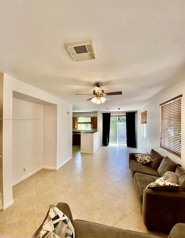 living room featuring light tile patterned floors, a ceiling fan, and baseboards