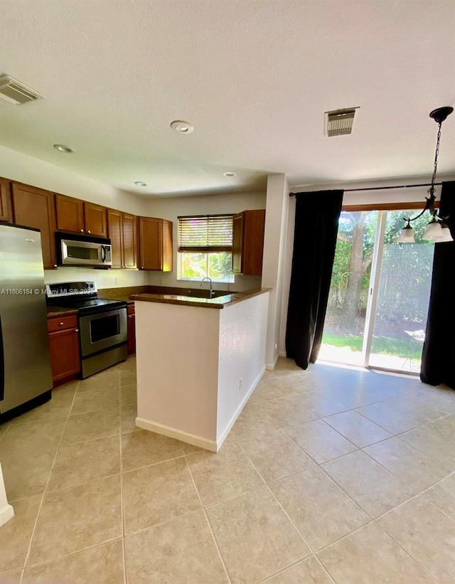kitchen with appliances with stainless steel finishes, dark countertops, plenty of natural light, light tile patterned floors, and recessed lighting