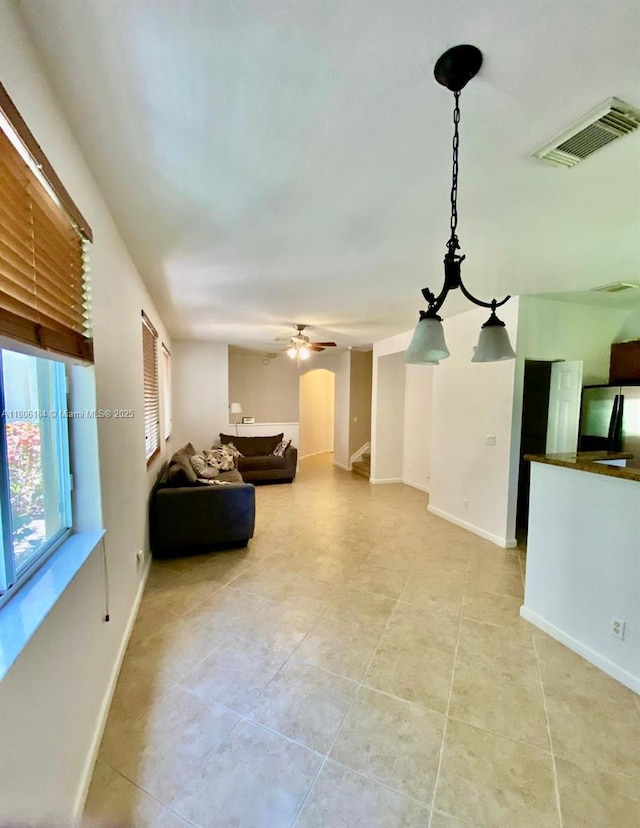 living area with light tile patterned floors, baseboards, and ceiling fan