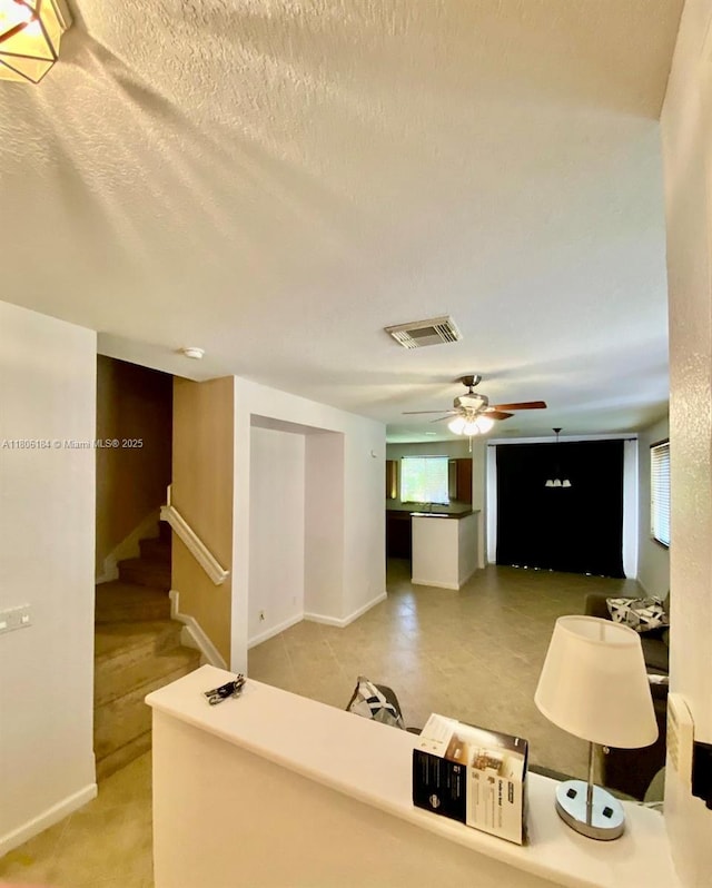 unfurnished living room with ceiling fan, baseboards, and stairs