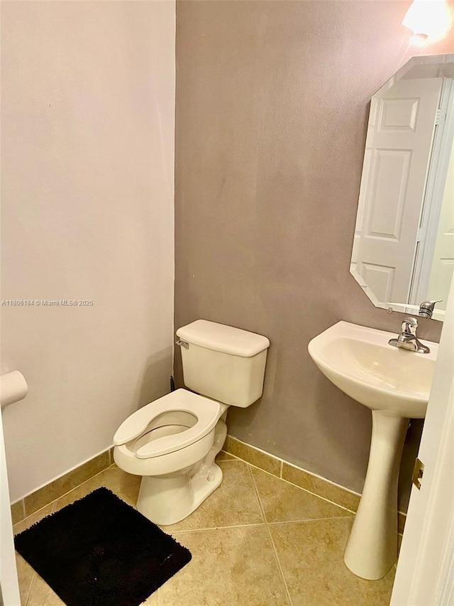 bathroom with tile patterned flooring, baseboards, and toilet