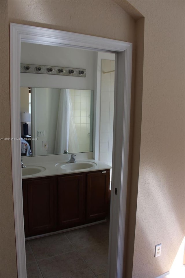 bathroom featuring a textured wall, tile patterned floors, and double vanity