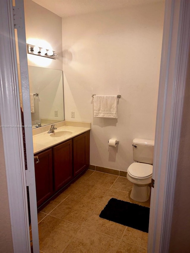 bathroom with vanity, toilet, and baseboards