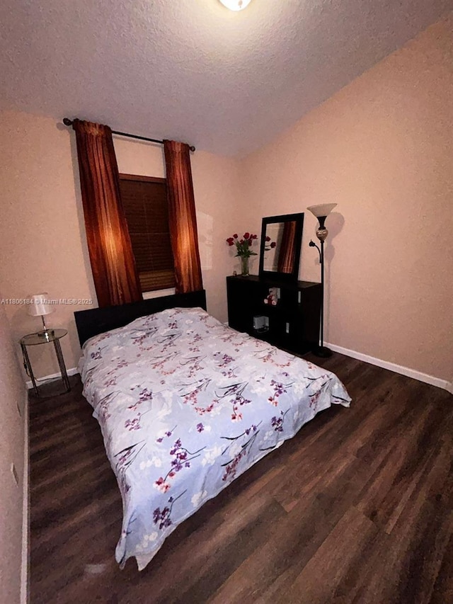 bedroom featuring wood finished floors, a textured ceiling, and baseboards
