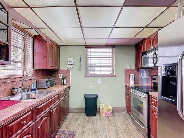 280 NW 45th St, Miami, FL 33127 - kitchen with stainless steel appliances, a sink, light wood-style flooring, backsplash, and a drop ceiling
