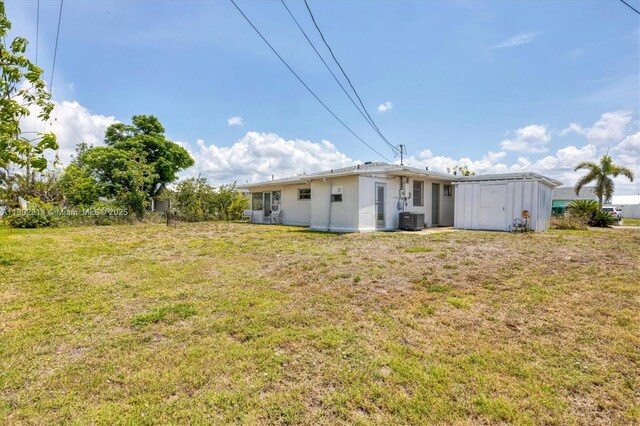 330 Lasayette Dr NE, Port Charlotte, FL 33952 - view of grassy yard with central air condition unit, a shed, and an outbuilding