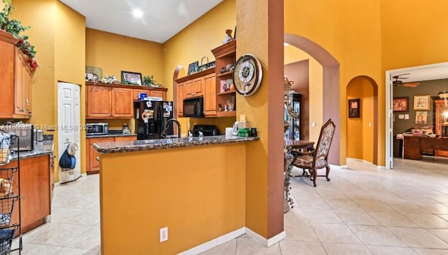 5764 NW 125th Ter, Coral Springs, FL 33076 - kitchen with a high ceiling, black appliances, arched walkways, light tile patterned floors, and dark stone counters