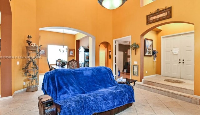 5764 NW 125th Ter, Coral Springs, FL 33076 - living room with light tile patterned floors, a towering ceiling, arched walkways, and baseboards