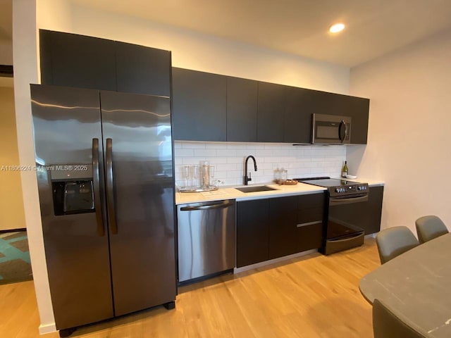 398 NE 5th St Unit 1619, Miami, FL 33132 - kitchen featuring stainless steel appliances, a sink, light wood-style floors, light countertops, and decorative backsplash