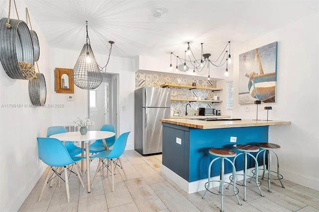 1411 NE 12th St, Fort Lauderdale, FL 33304 - kitchen with freestanding refrigerator, wooden counters, a chandelier, baseboards, and light wood finished floors