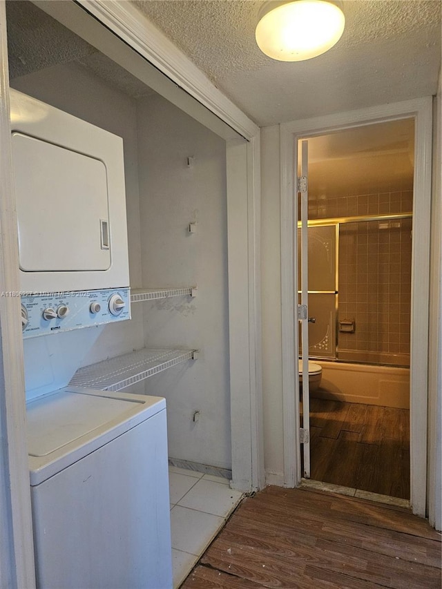 8620 N Sherman Cir Unit 202, Miramar, FL 33025 - laundry area with stacked washer and clothes dryer, wood finished floors, and a textured ceiling