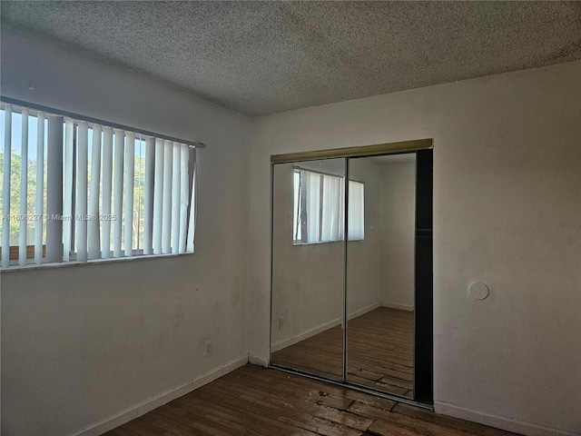 8620 N Sherman Cir Unit 202, Miramar, FL 33025 - unfurnished bedroom with wood finished floors, a closet, a textured ceiling, and baseboards