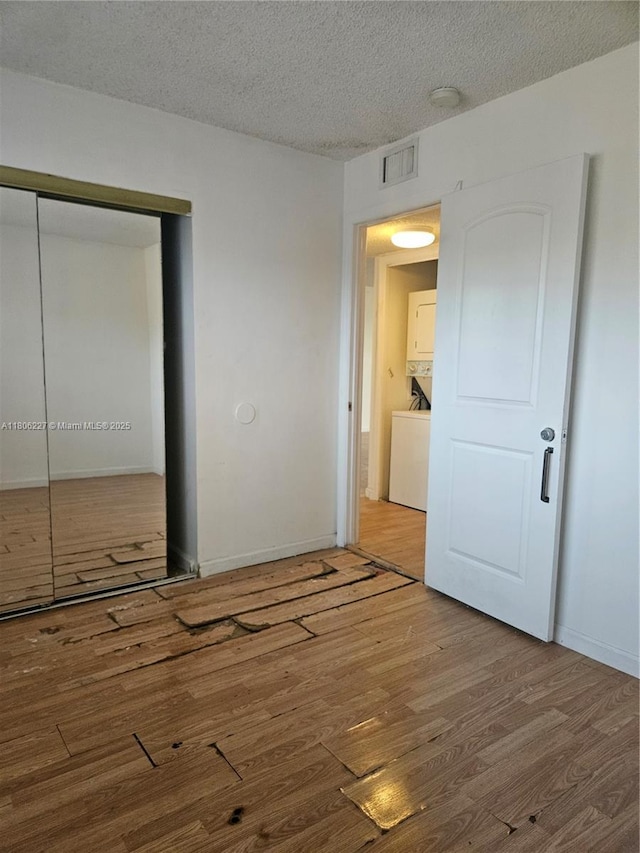 8620 N Sherman Cir Unit 202, Miramar, FL 33025 - unfurnished bedroom featuring stacked washing machine and dryer, wood finished floors, a closet, a textured ceiling, and baseboards