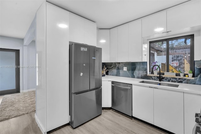 1635 NE 174th St, North Miami Beach, FL 33162 - kitchen featuring stainless steel appliances, light wood finished floors, a sink, light countertops, and white cabinets