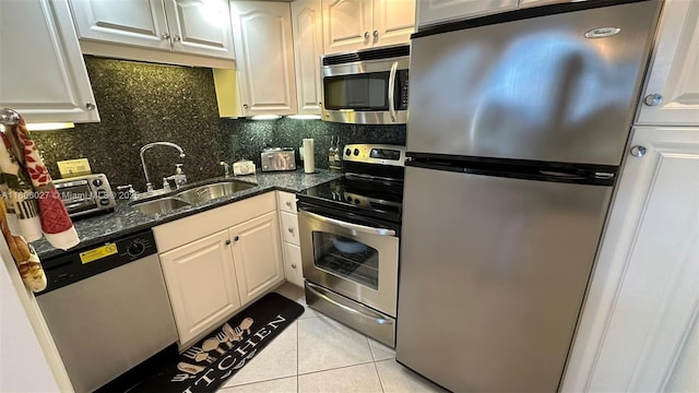 180 Seaview Ct Unit 706, Marco Island, FL 34145 - kitchen with stainless steel appliances, a sink, light tile patterned flooring, tasteful backsplash, and dark stone counters