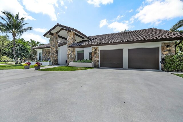 11850 SW 42nd Ct, Davie, FL 33330 - view of front facade featuring stone siding, driveway, a tiled roof, and an attached garage