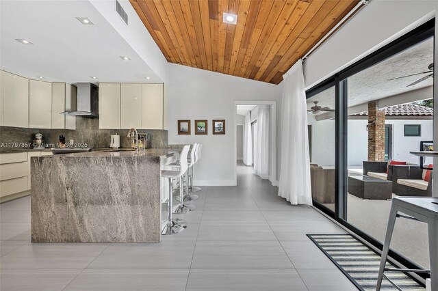 11850 SW 42nd Ct, Davie, FL 33330 - kitchen featuring wall chimney range hood, modern cabinets, tasteful backsplash, a ceiling fan, and a kitchen bar